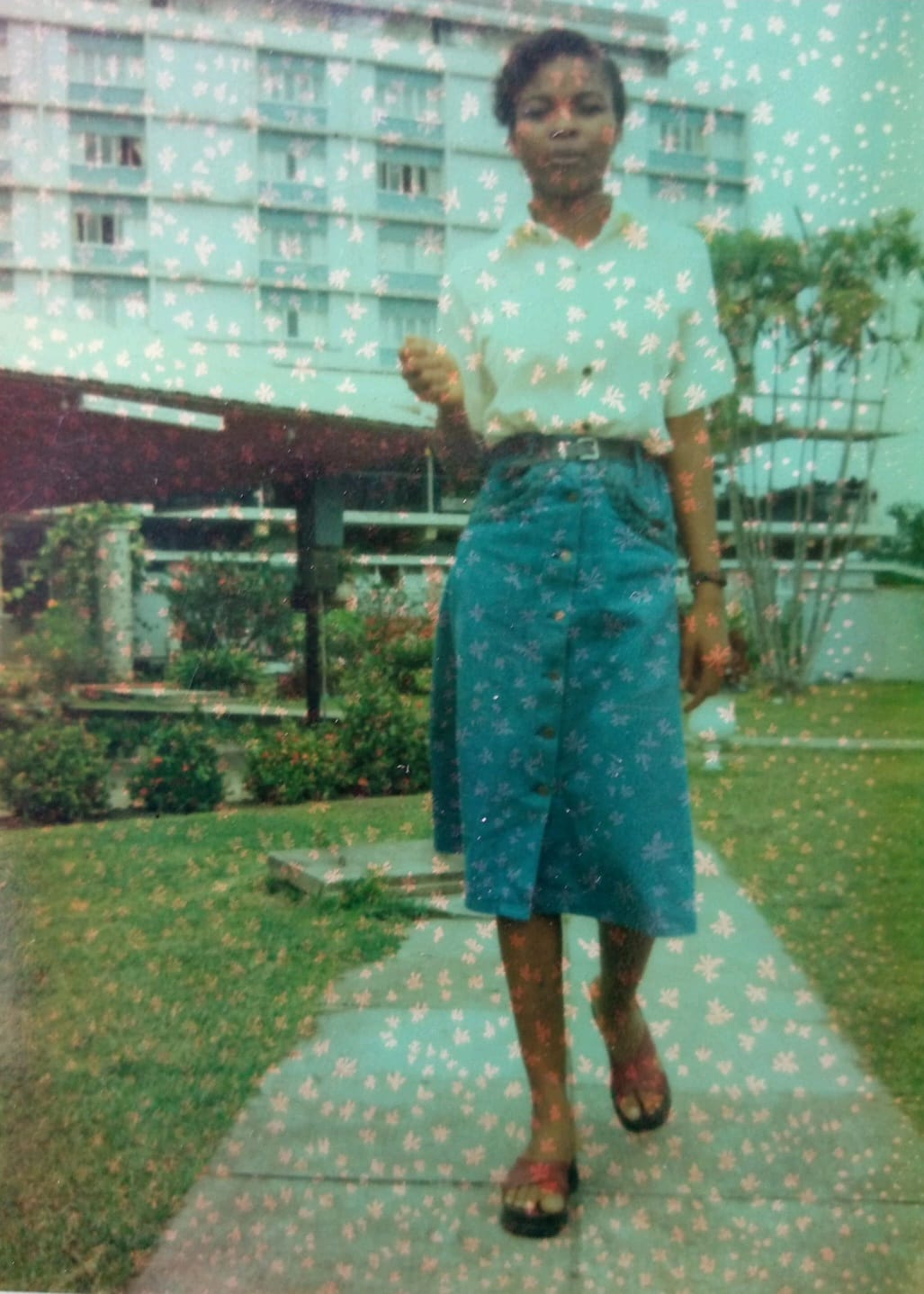 A vintage photograph walking a garden path in a white blouse and denim skirt