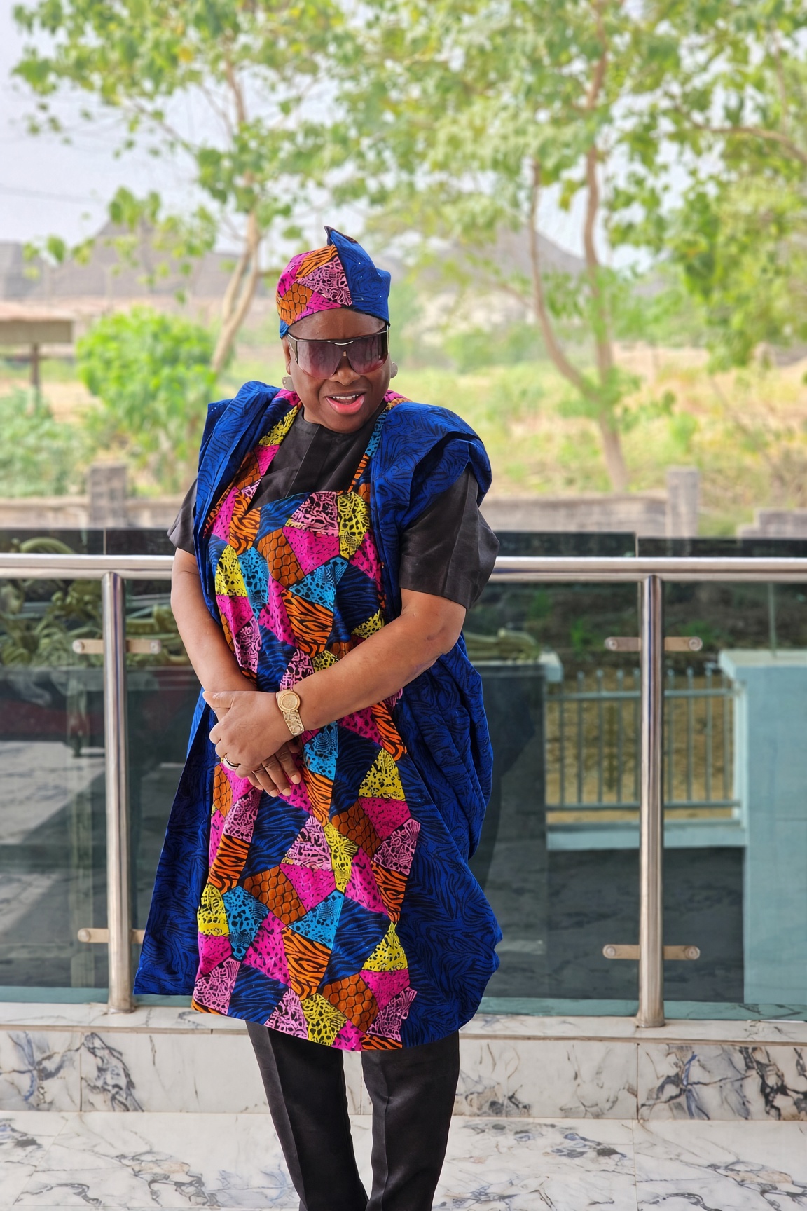Gloria Nzenwa in a vibrant patchwork dress and blue head wrap